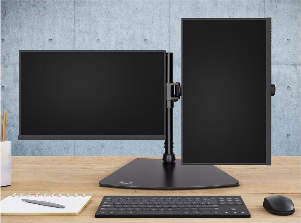  A stand on a desk with two monitors mounted: one in horizontal orientation, and the other in vertical orientation. In front of it are a notebook with pen on it, a wireless keyboard and a mouse.  